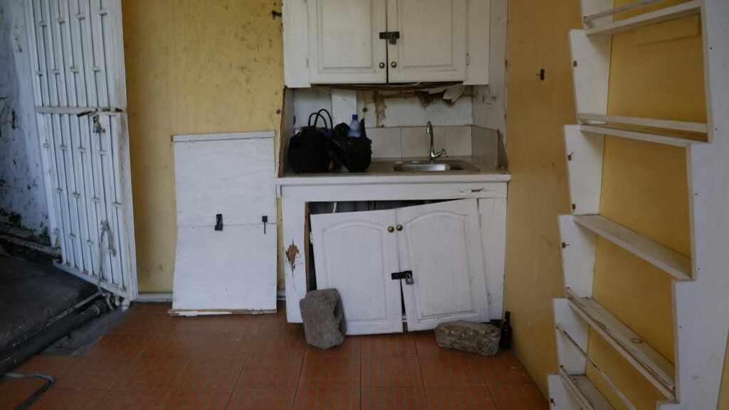 una cocina deteriorada con una pared amarilla como fondo.