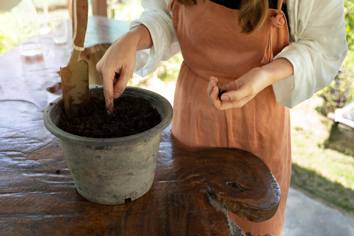 una mujer que prepara un mezcla de compost con tierra para macetas.