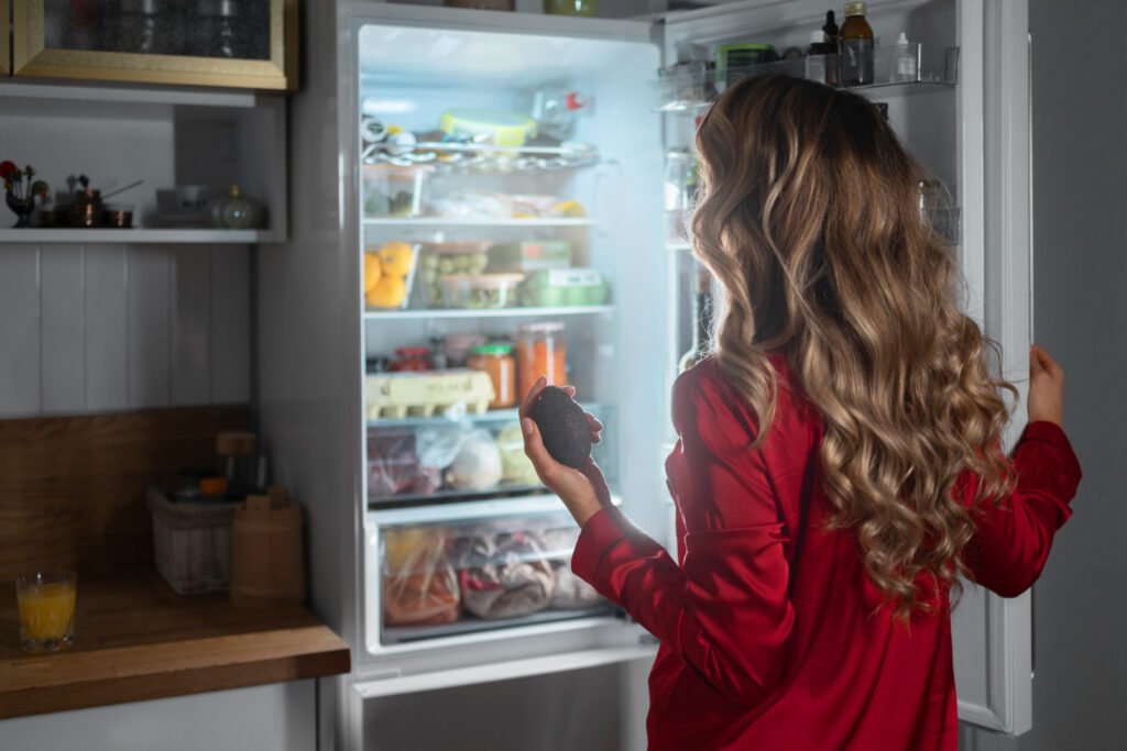 Mujer viendo el interior de su nevera y cerciorándose de que tenga la temperatura optima para evitar desperdicio de energía, un consejos imperdible si quieres ahorrar energía en casa.