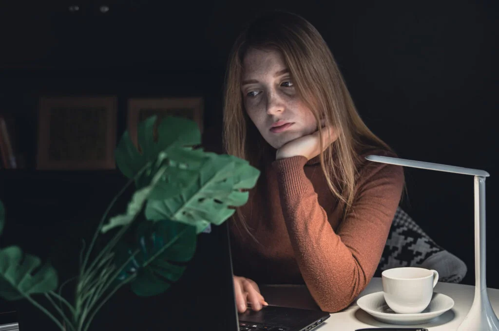 mujer observando como la mala iluminación afecta los cuidados de sus plantas de interior.